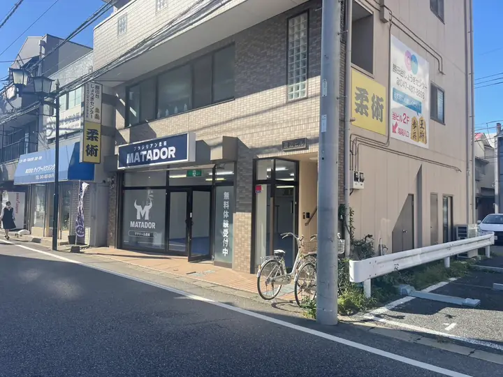 通りから見たマタドール柔術 勝田台（渡辺ビル1階、紺色のMATADOR看板）